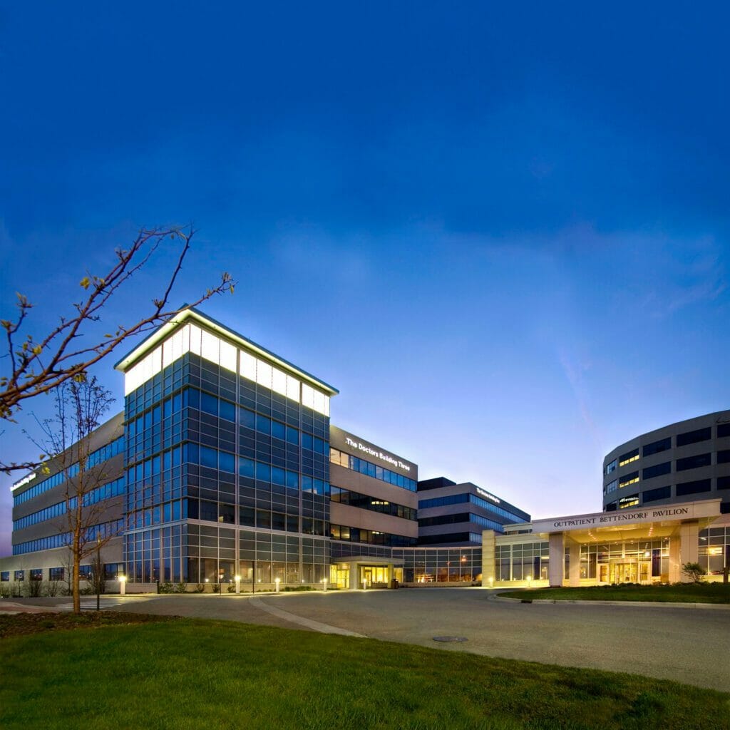 Exterior view of St. Alexius Doctors Office Building Three at night with a mostly glass exterior and porte-cochère with the Outpatient Bettendorf Pavilion sign on it