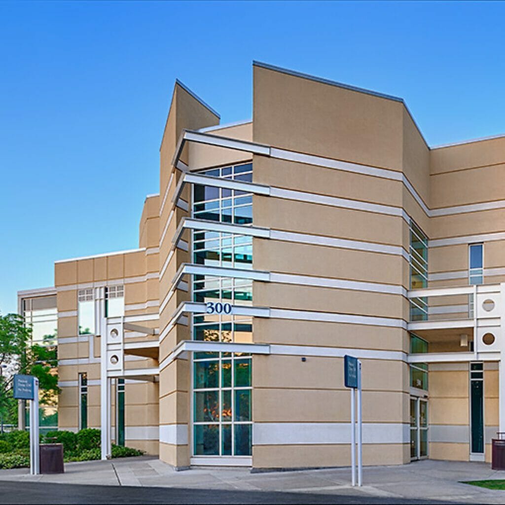 Exterior view of a medical office building with tan and silver horizontal lines on the exterior with bright blue sky