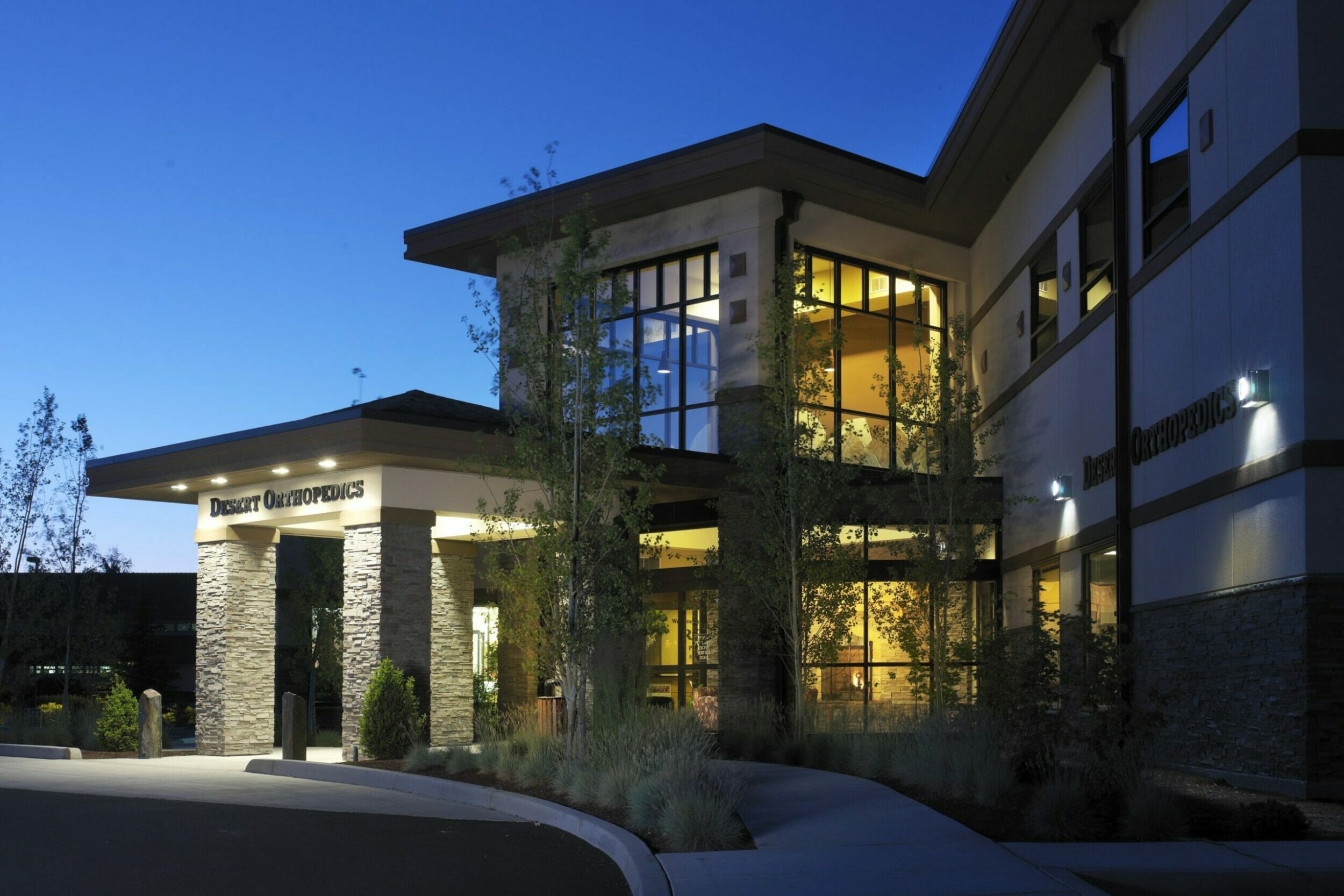 Exterior close-up shot of the entrance to Bend Surgey Center with the Desert Orthopedics sign above the door and glowing lights inside