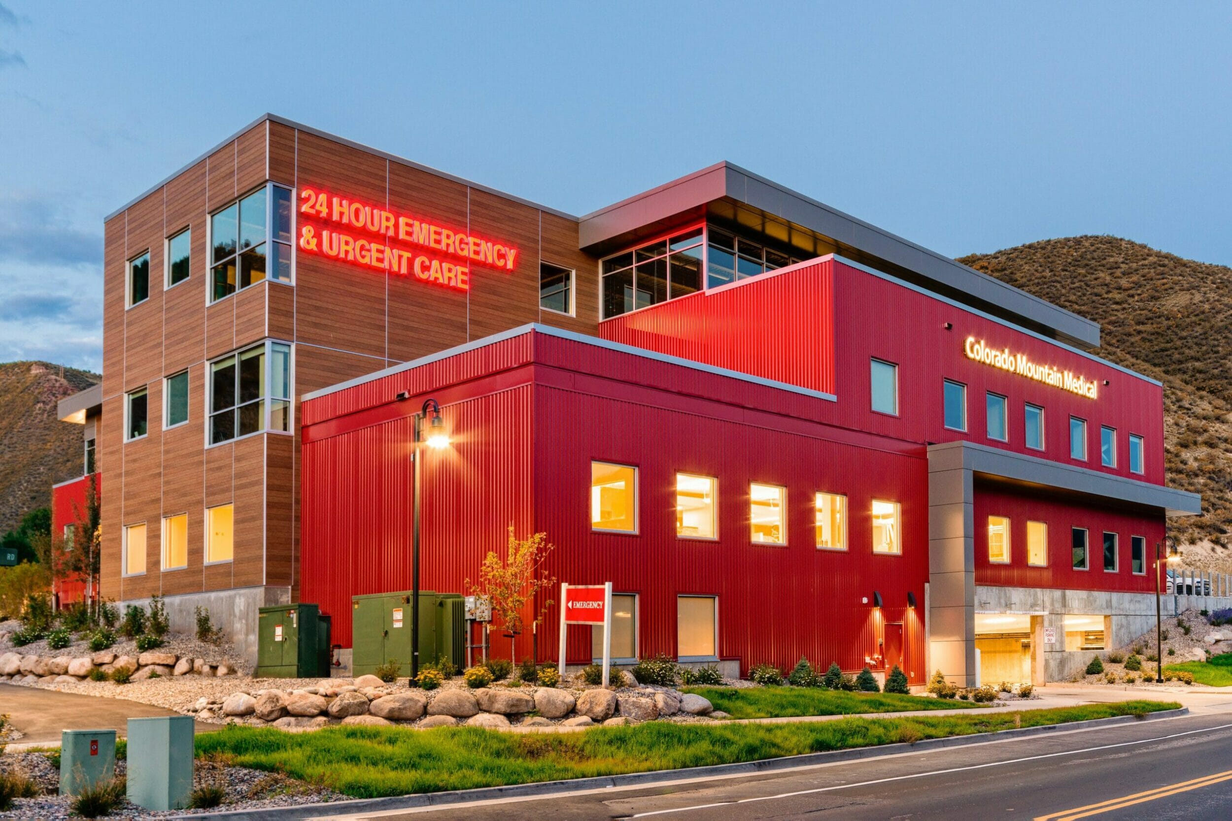 Exterior view of red and wood medical center with lights on at dusk
