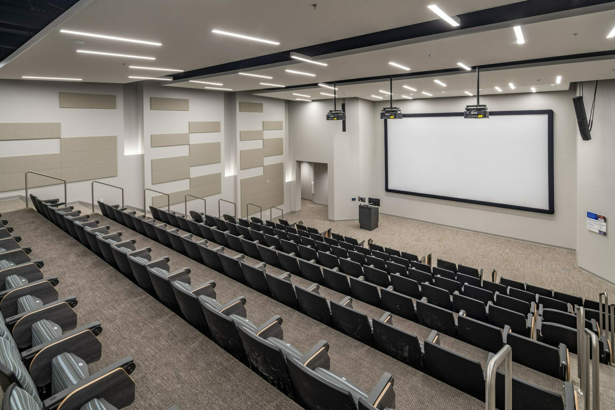 Gray lecture hall inside CHI Cancer Center with large projector screen and multiple auditorium seats