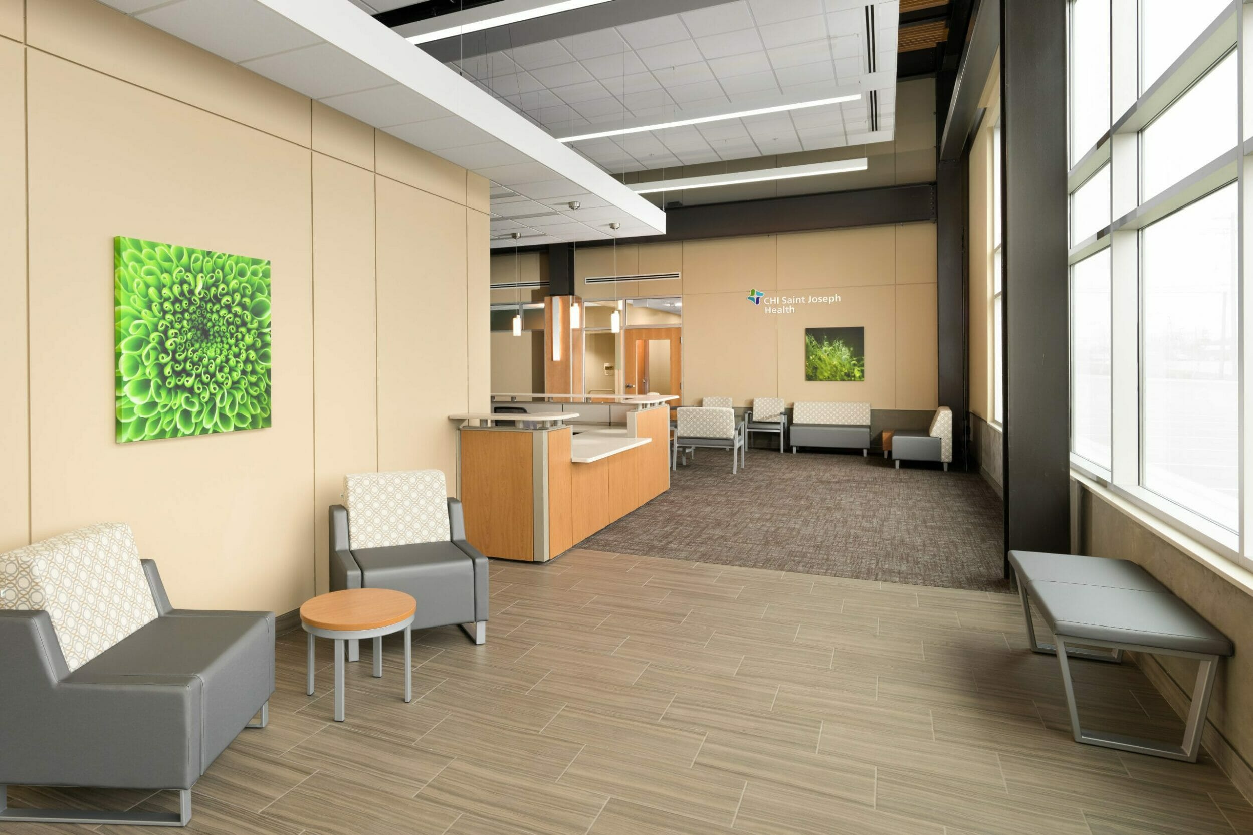 CHI Saint Joseph Health waiting room and fronk desk with multiple seating areas, tile and carpeted floors, and light wood walls