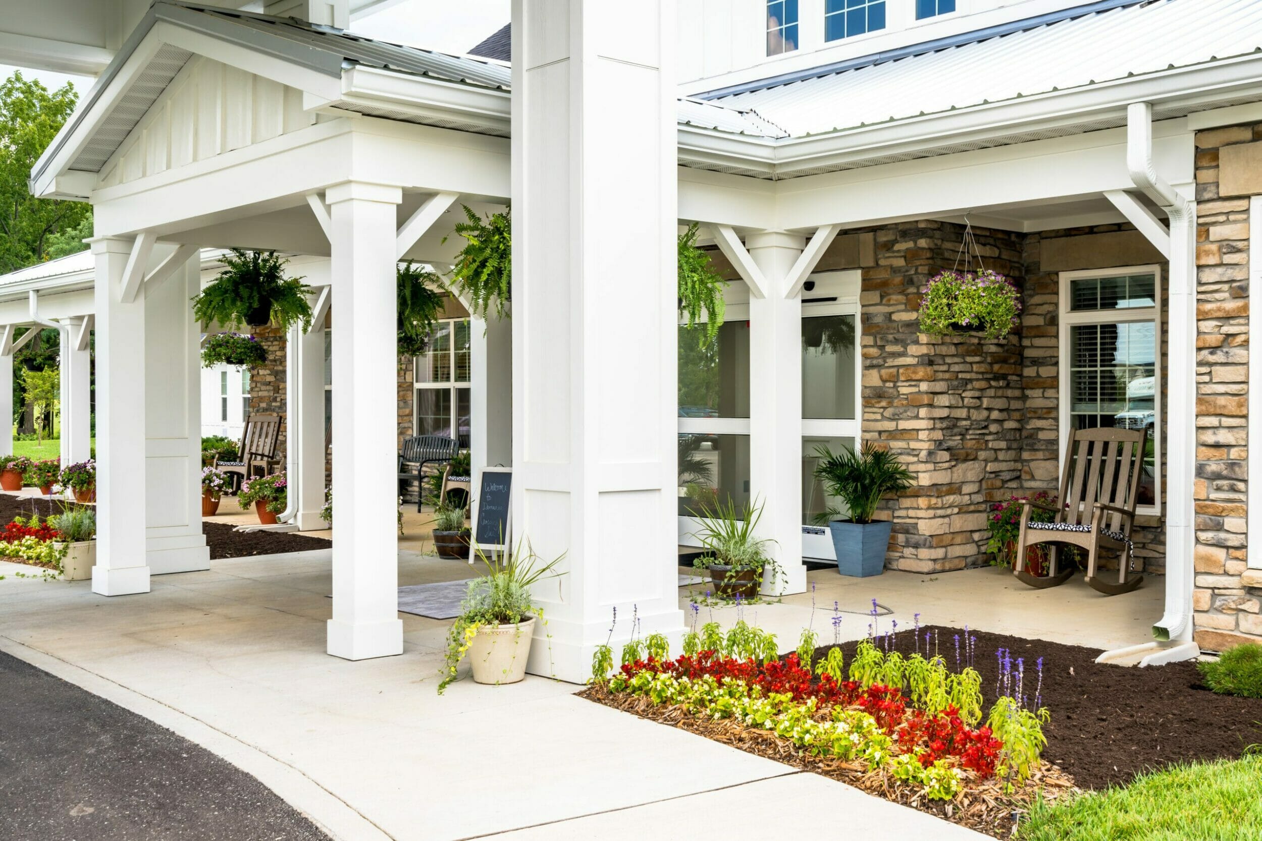 Close-up shot of front door and patio of Demaree Crossing senior living with plants hanging and planted in the ground