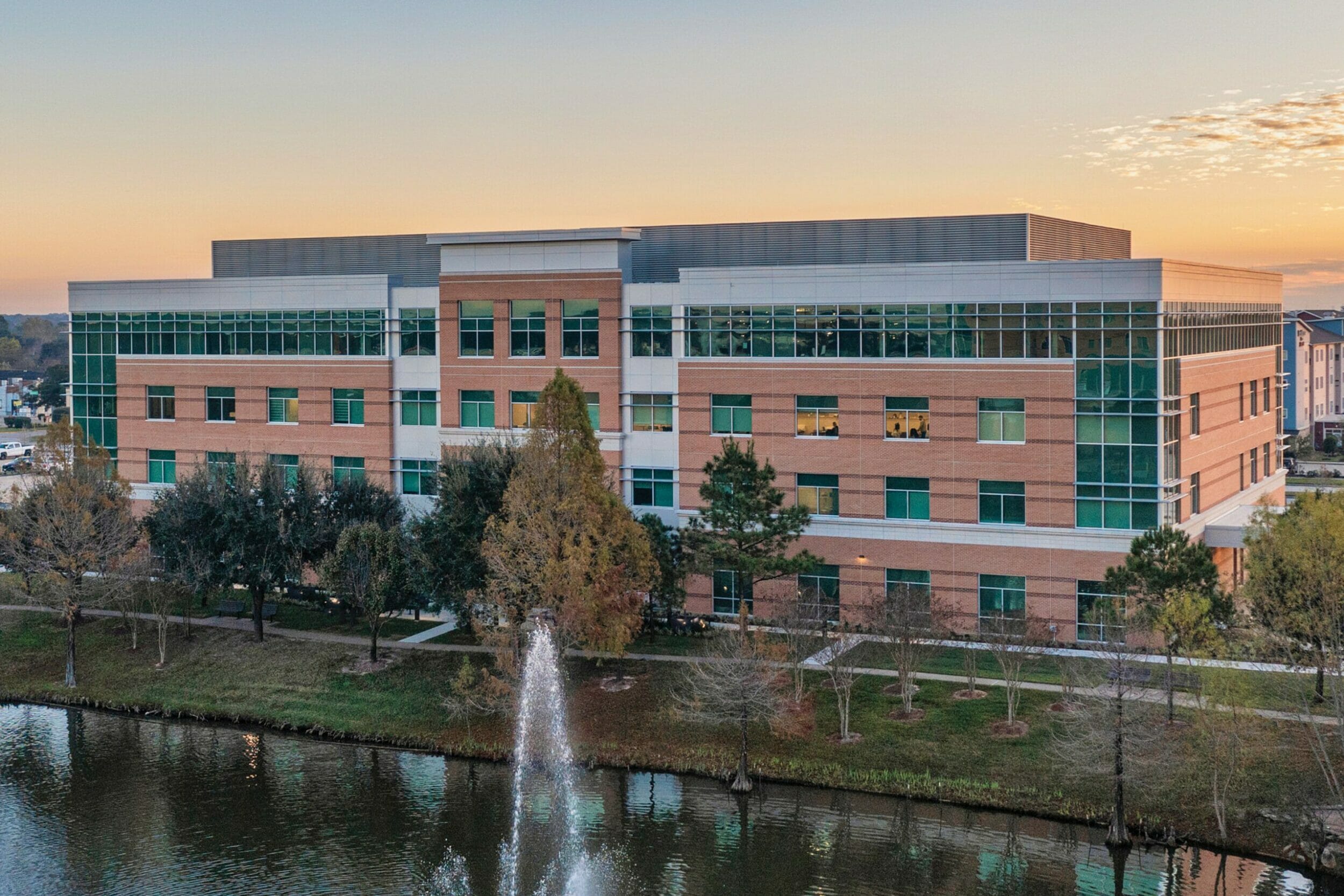 Drone view of the side of HCA Houston Healthcare North Cypress medical office building with pond and water fountain in front of the building view