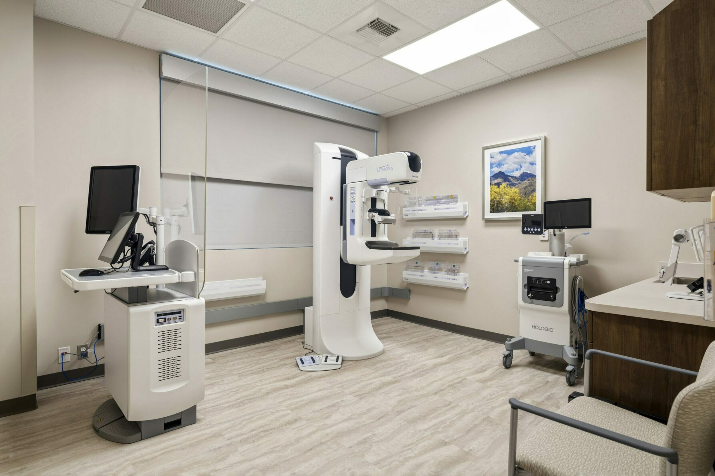 Beige medical office room with a Selenia® Dimensions® 2D/3D™ Digital Mammography System machine and dark wood cabinets