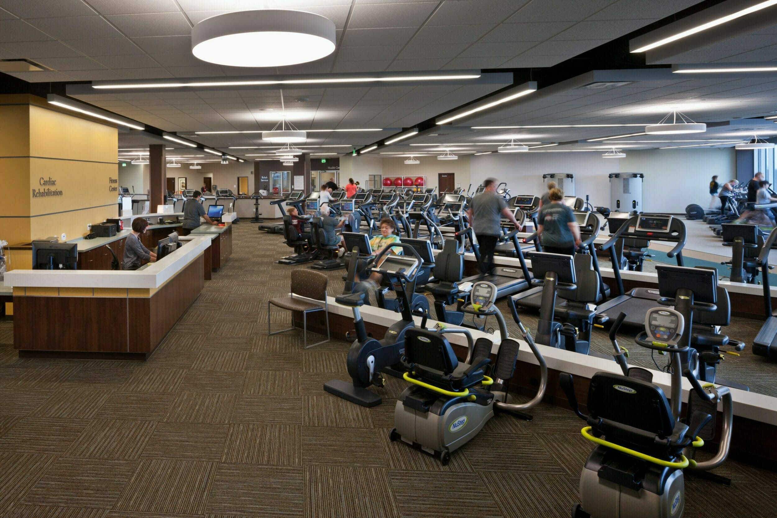 gym inside cardiac rehabilitation center with people using various workout equipments