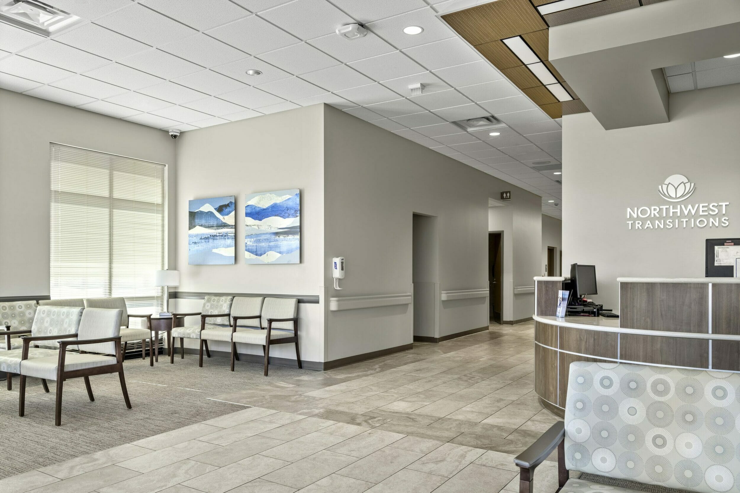 NorthWest Transitions gray lobby with tile and capret floor with multiple chairs to sit and a wood front desk