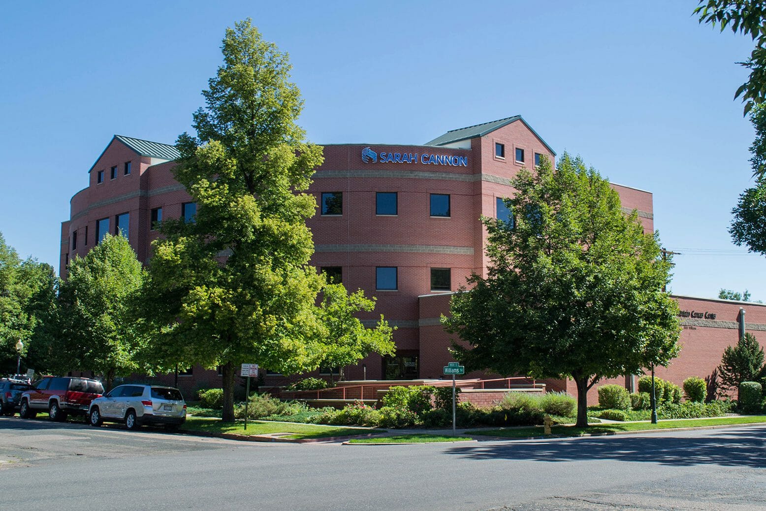 View of brick exterior of Rocky Mountain Cancer Center with sarah cannon research institute logo on top of building from across the street