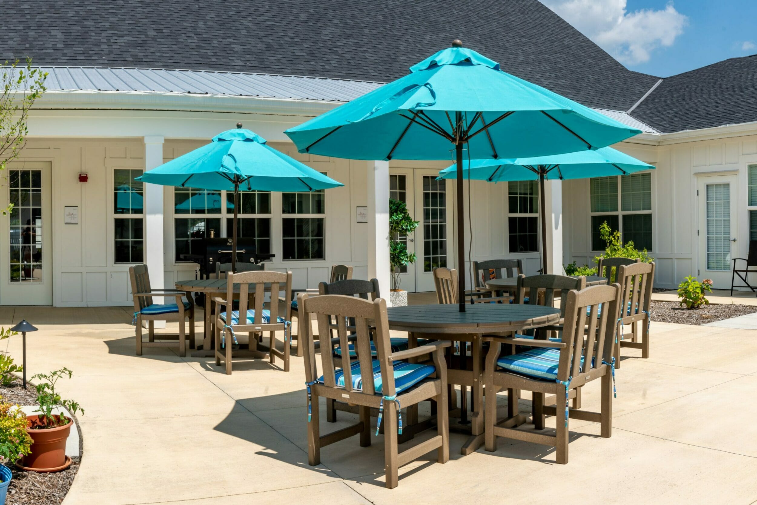 Outdoor patio with tables and chairs with teal umbrellas with plants