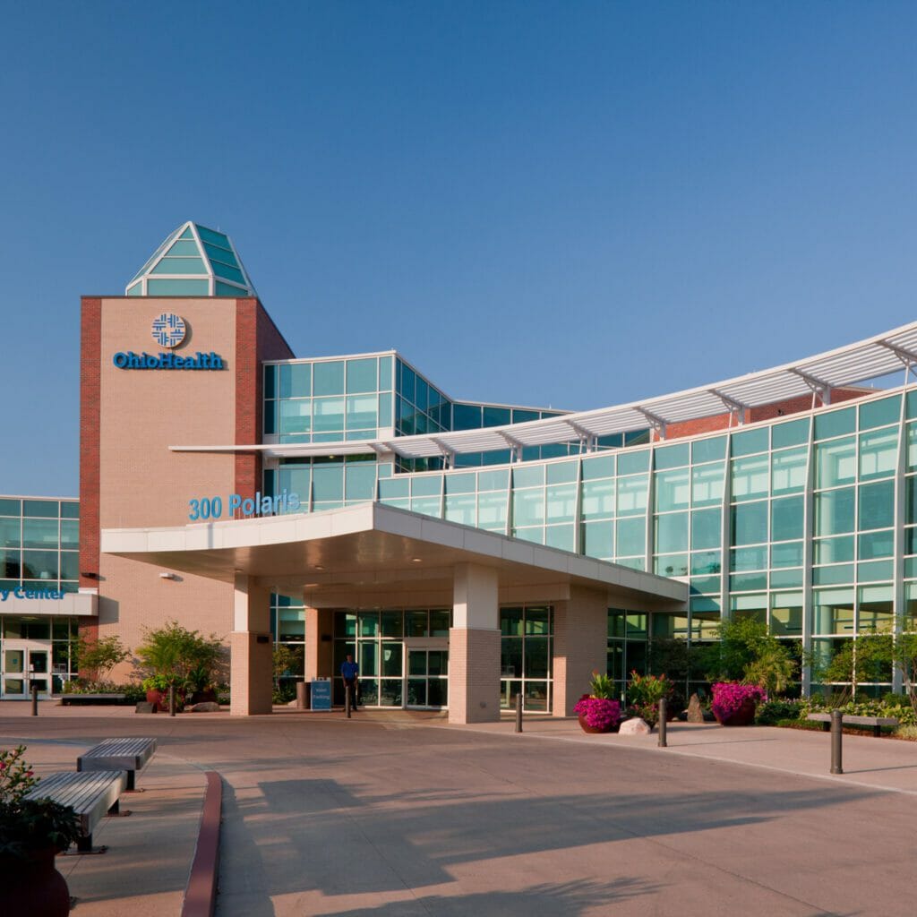 Exterior of Ohio Health Medical Center with large, blue-tinted glass windows behind the porte-cochère with the address on the front