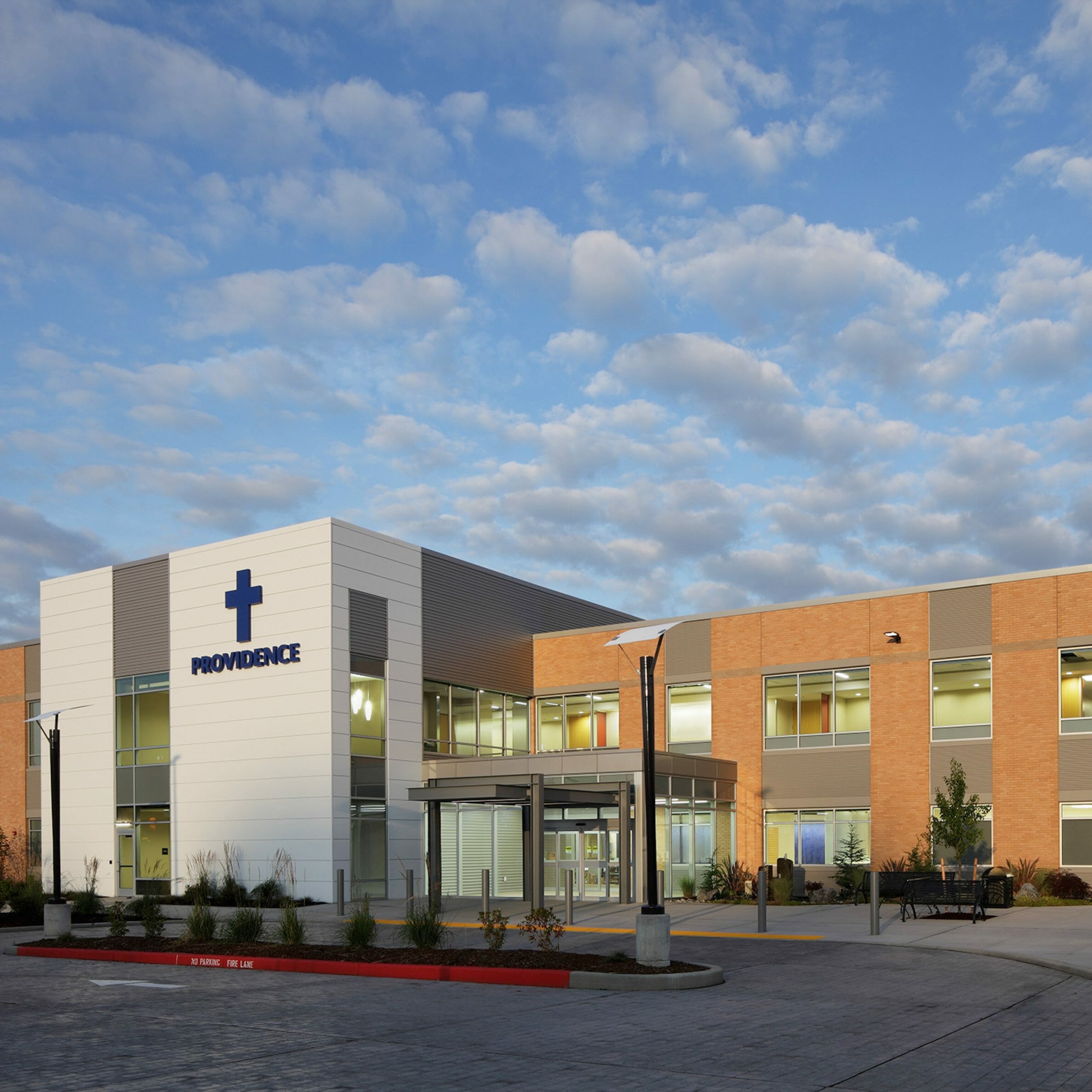 Exterior view of Providence Monroe Family Medicine with a brick exterior and silver and gray accent walls where the blue Providence letters and cross sign are
