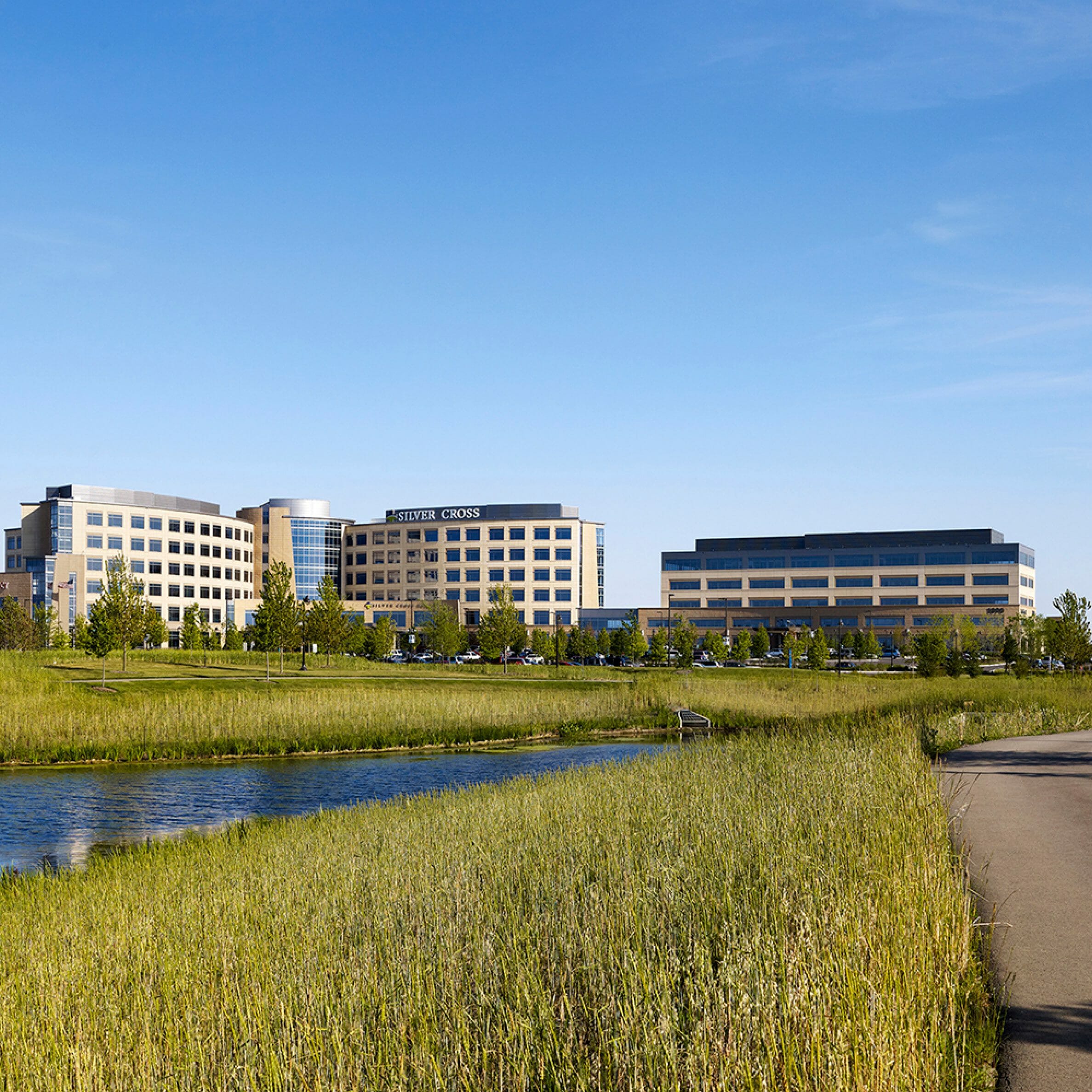 wide shot exterior view of silver cross hospital and medical office building. Pond, greenery and trails