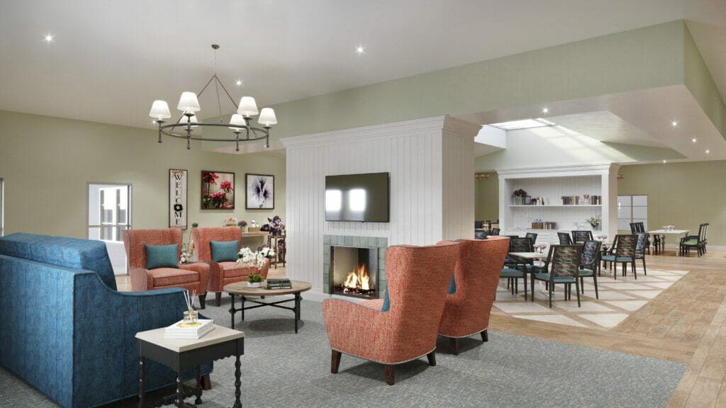 An interior view of Atlee senior living community. Red chairs, blue couch, fire place.