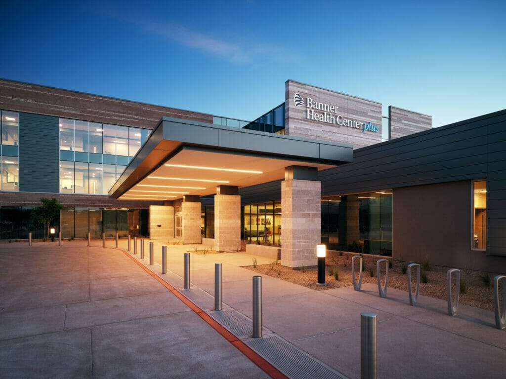 Close-up shot of Banner Health Center plus at night with lights over the entrance area with stone and cement accents