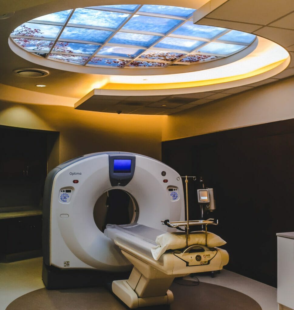 GE Optima CT Scan machine in dark room with fake sky and tree ceiling